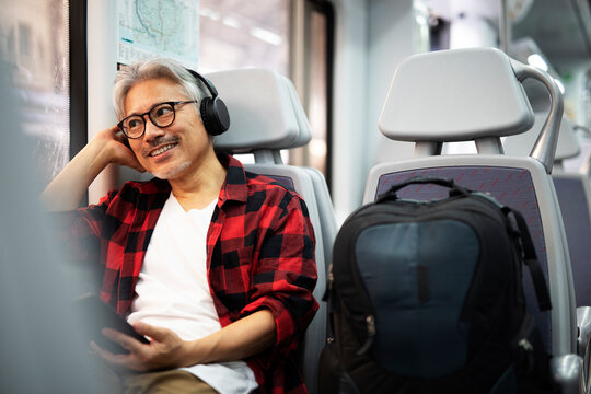 Senior man traveling by train. Man listening the music while enjoying in travel