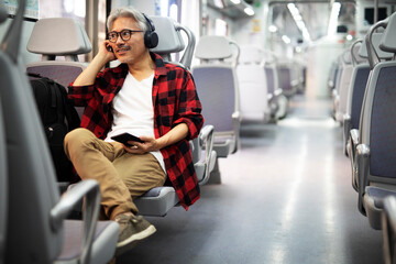 Fototapeta na wymiar Senior man traveling by train. Man listening the music while enjoying in travel