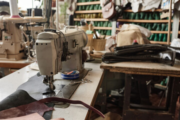 Close-up of workplace of tailor with sewing machine on it in the workshop