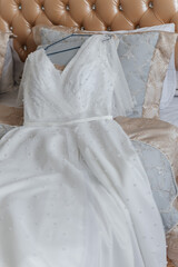 A beautiful wedding dress lies on the bed.