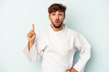 Young mixed race man doing karate isolated on blue background having some great idea, concept of creativity.