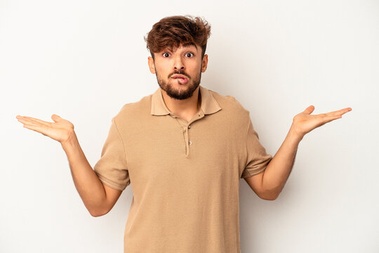 Young mixed race man isolated on grey background confused and doubtful shrugging shoulders to hold a copy space.
