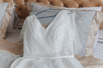 A beautiful wedding dress lies on the bed.