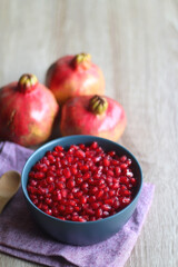 Bowl filled with pomegranate seeds and pomegranate fruit on a table. Selective focus.