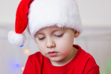 Portrait of a cute boy in a Santa Claus hat. Funny smiling child.