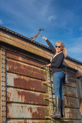 Adult woman with sunglasses climbing an abandoned train car ladder.