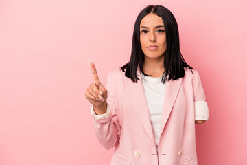 Young caucasian woman with one arm isolated on pink background showing number one with finger.