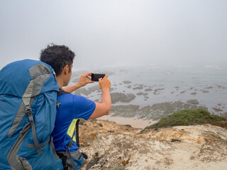 hiker taking a photo at the Brejo beach on the fishermen's route in Portugal