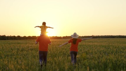 Mother, dad, daughter are walking in the summer park. Family travel. Child on the shoulders of dad, mom, happy childhood. Happy family of farmers with a child cheerfully run in a wheat field at sunset