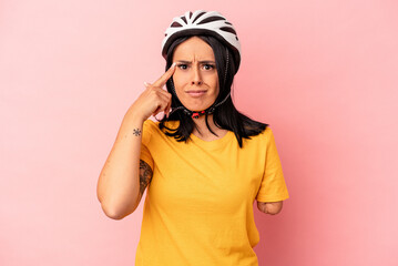 Young caucasian woman with one arm wearing a bike helmet isolated on pink background showing a disappointment gesture with forefinger.