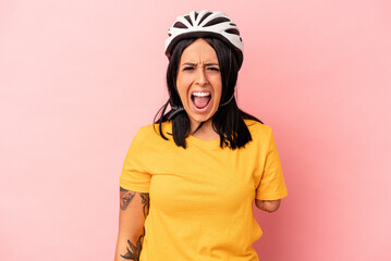 Young caucasian woman with one arm wearing a bike helmet isolated on pink background screaming very angry and aggressive.