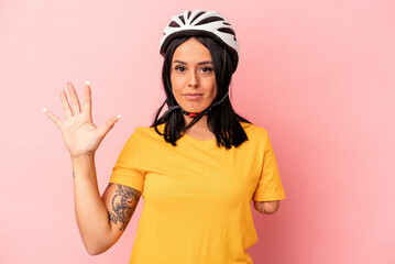 Young caucasian woman with one arm wearing a bike helmet isolated on pink background smiling cheerful showing number five with fingers.