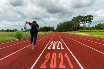 The start into the new year 2022. Start up of runner man running on race track go to Goal of Success.  People running as part of Number 2022.  Holiday sport and health care Concept