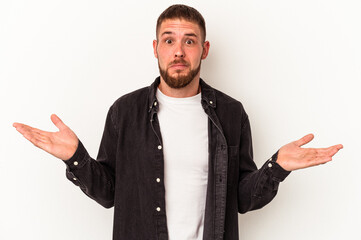 Young caucasian man with diastema isolated on white background shrugs shoulders and open eyes confused.