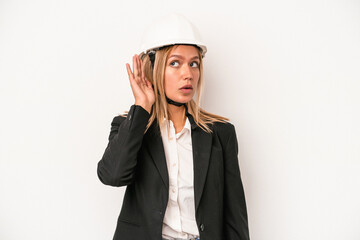 Young caucasian architect woman wearing a helmet isolated on white background trying to listening a gossip.