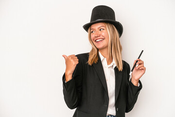 Young caucasian wizard woman holding wand isolated on white background points with thumb finger...