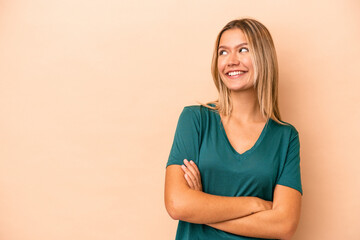 Young caucasian woman isolated on beige background smiling confident with crossed arms.