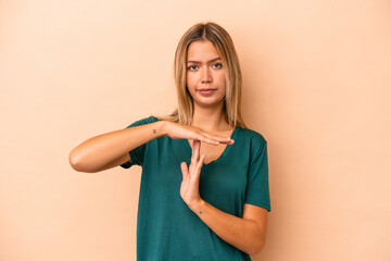 Young caucasian woman isolated on beige background showing a timeout gesture.