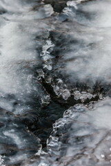 Icicles and frost on a snow-covered frozen river