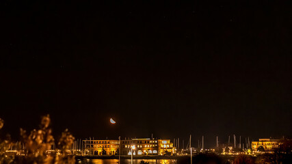 Mond geht am Abend über dem Hafen von Rostock Warnemünde auf
