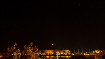 Fototapeta na wymiar Mond geht am Abend über dem Hafen von Rostock Warnemünde auf
