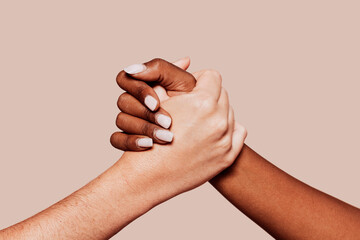 Close up multiracial woman couple with black and caucasian hands holding each other in tolerance unity love and anti racism concept. Studio shot, pastel beige background. - Powered by Adobe