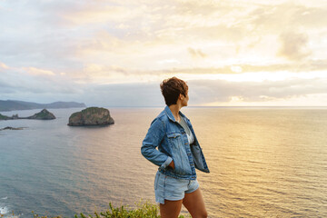 Adventurous woman with backpack in a cliff. Horizontal view of caucasian woman traveling and sightseeing outdoors.