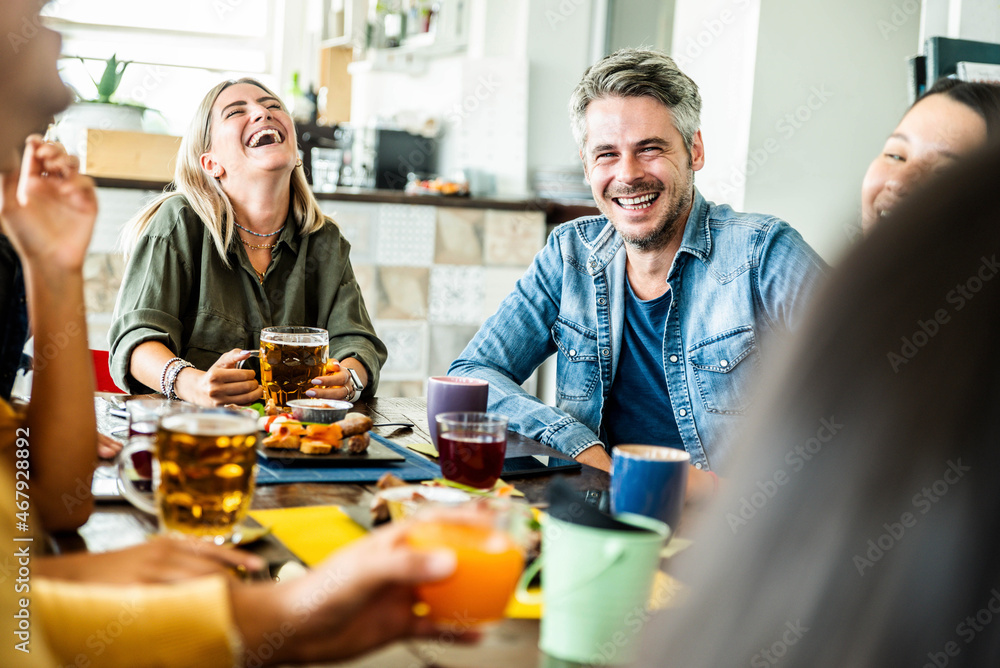 Wall mural Happy friends having lunch brunch together at cafe bar restaurant - Mixed age group of people having fun laughing and talking while having dinner at dining table - Friendship and youth concept