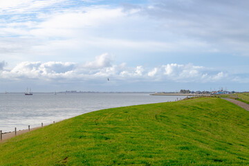 Slope hill and green grass on the dyke under blue sky and white clouds, The dike between polder...