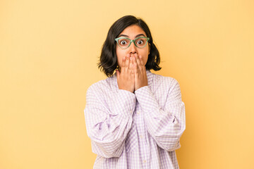 Young latin woman isolated on yellow background shocked, covering mouth with hands, anxious to discover something new.