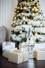 Big beautiful New Year tree with gifts in a white decorated hall for the New Year