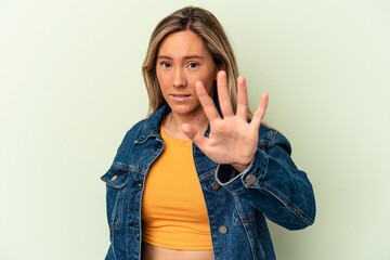 Young caucasian woman isolated on green background being shocked due to an imminent danger