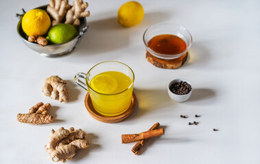 Healthy winter beverage with ginger, turmeric, cinnamon stick, lemon, honey and black pepper