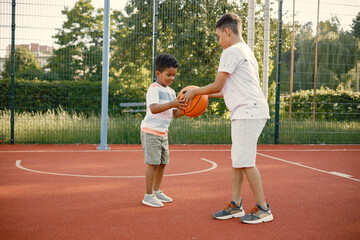 Two brothers playing basketball in basketball court together
