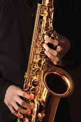 saxophonist, musician playing the saxophone, hands close-up, wind instrument, music background