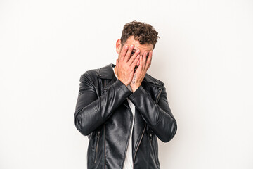 Young caucasian man isolated on white background blink at the camera through fingers, embarrassed covering face.