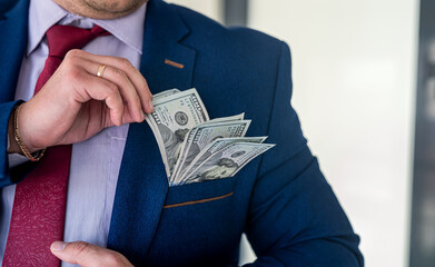 businessman placing dollar money into his pocket as after a successful deal or bribe