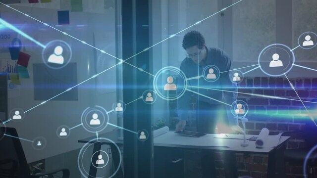Animation of network of people icons over man working with tablet in office