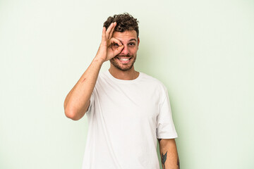 Fototapeta premium Young caucasian man isolated on green background excited keeping ok gesture on eye.