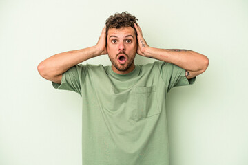 Young caucasian man isolated on green background being shocked, she has remembered important...