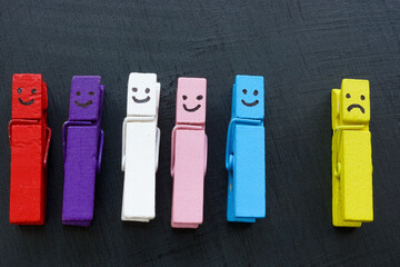 Clothespins with happy faces and unhappy ones. Bullying and inclusion concept.