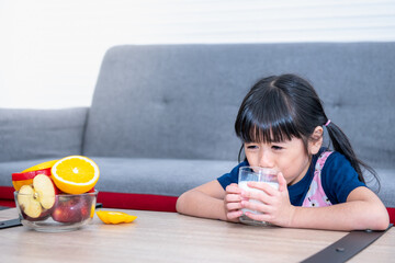 Asian girl 6 years old sitting on a table which a bowl of fresh fruit is placed And was forced to...