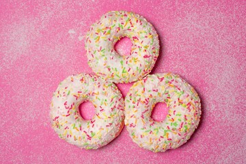 Three donuts on pink background. - obrazy, fototapety, plakaty