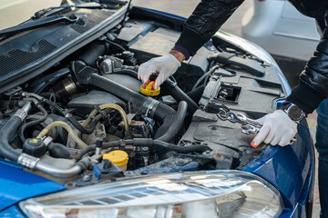hands of a strong man mechanic in gloves repairs the car under the hood.