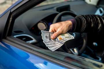 a strong bad criminal counts a large amount of dollar bills inside a car.