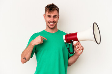 Young caucasian man holding megaphone isolated on white background person pointing by hand to a shirt copy space, proud and confident