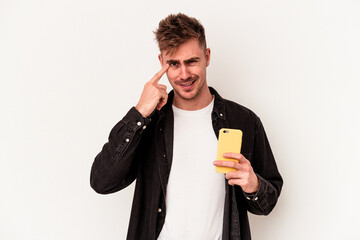 Young caucasian man holding a mobile phone isolated on white background showing a disappointment gesture with forefinger.