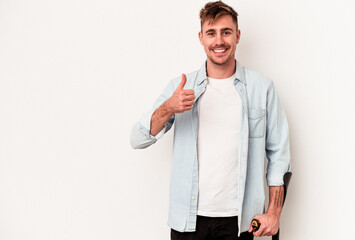 Young caucasian man holding crutch isolated on white background smiling and raising thumb up
