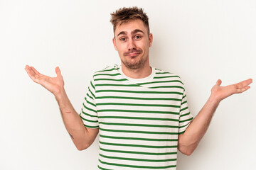 Young caucasian man isolated on white background doubting and shrugging shoulders in questioning...