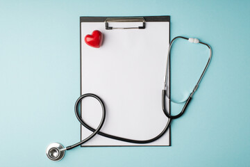 Top view photo of stethoscope clipboard with paper sheet and small red heart on isolated pastel blue background with blank space